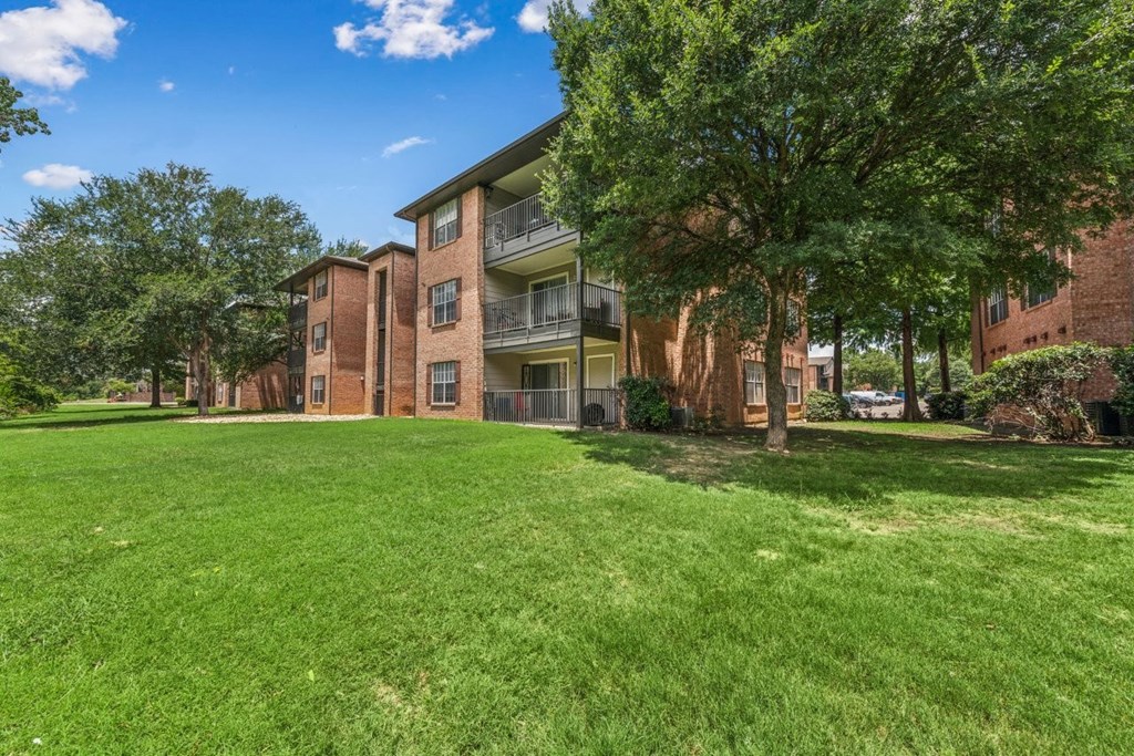 A grassy area in front of a brick apartment building.