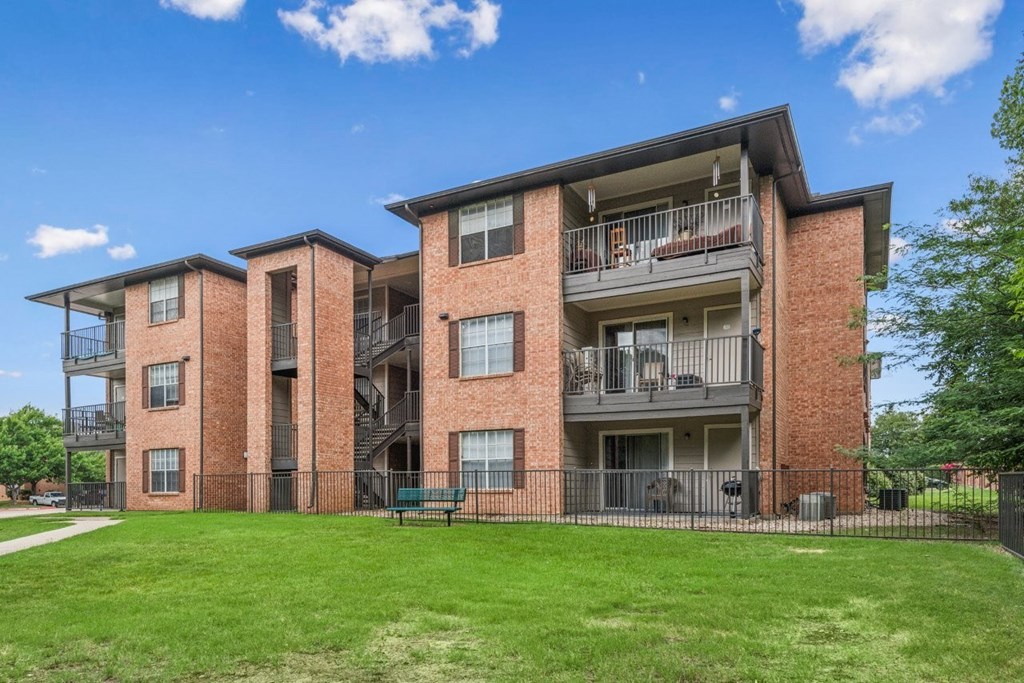 A large brick apartment building with a green lawn in front.