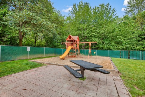 A playground with a slide and a picnic table.