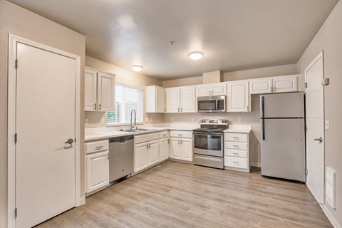 A kitchen with white cabinets and appliances.