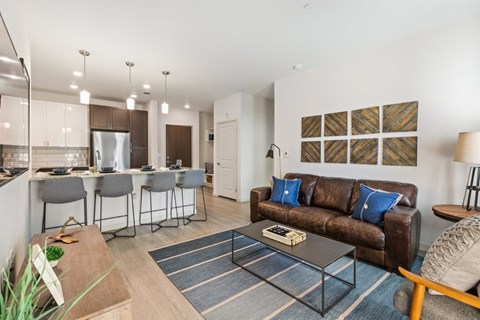 A modern living room with a brown couch and a dining table with four chairs.
