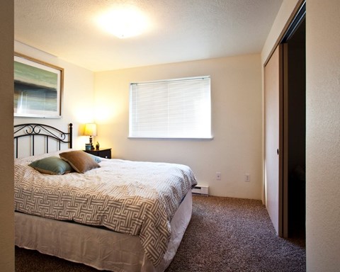 A bedroom with a bed, nightstand, and window.