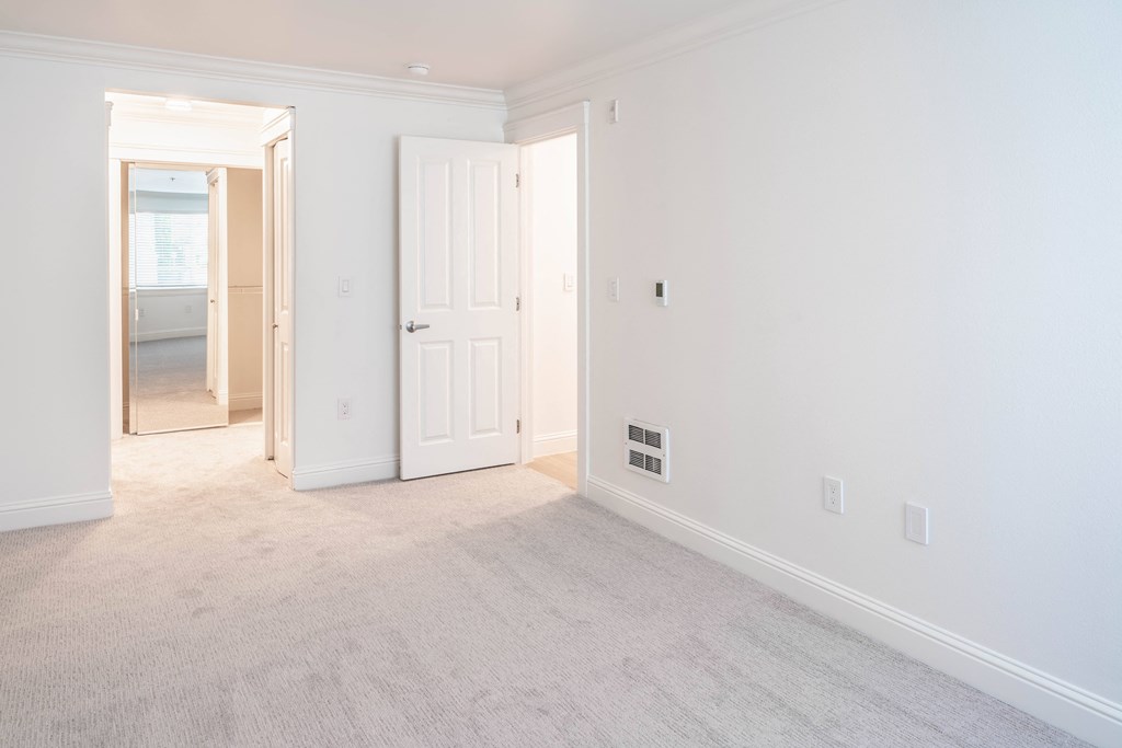 a bedroom with white walls and carpet