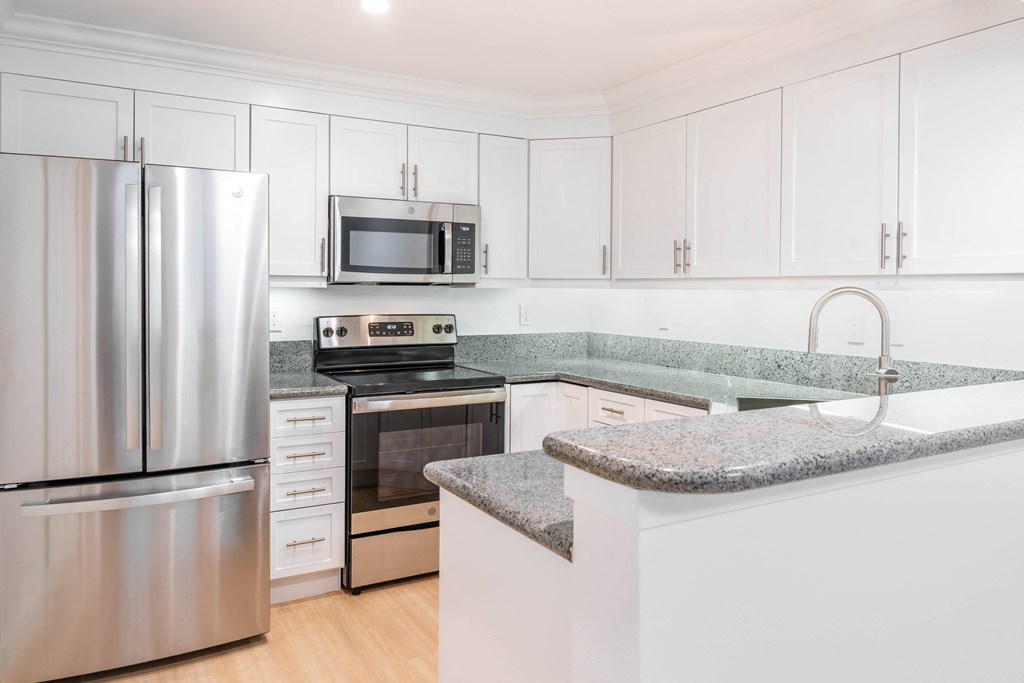 a kitchen with white cabinets and granite countertops