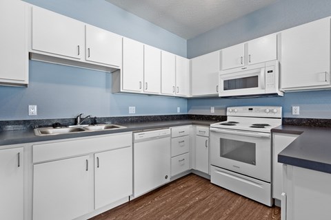 A kitchen with white cabinets and a white stove top oven.