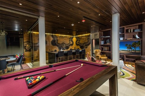 A pool table is in the middle of a room with a wooden ceiling.