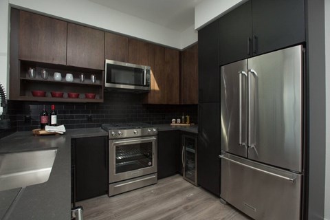 A modern kitchen with a stainless steel refrigerator and oven.