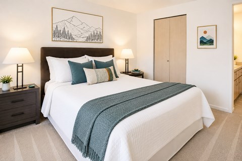 A bedroom with a large bed and a mountain painting on the wall.