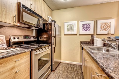 A kitchen with a refrigerator, oven, and sink.