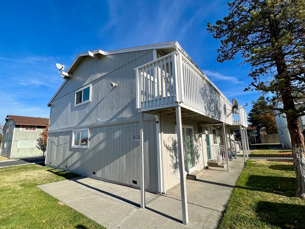 a gray building with a balcony and a sidewalk