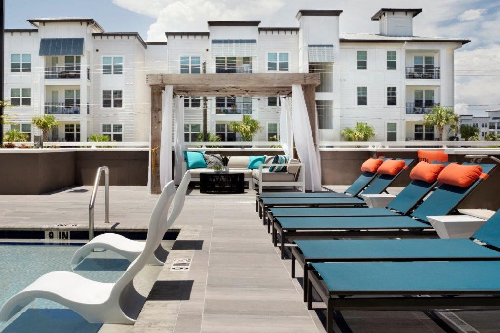 a pool with lounge chairs and a fire pit in front of an apartment building