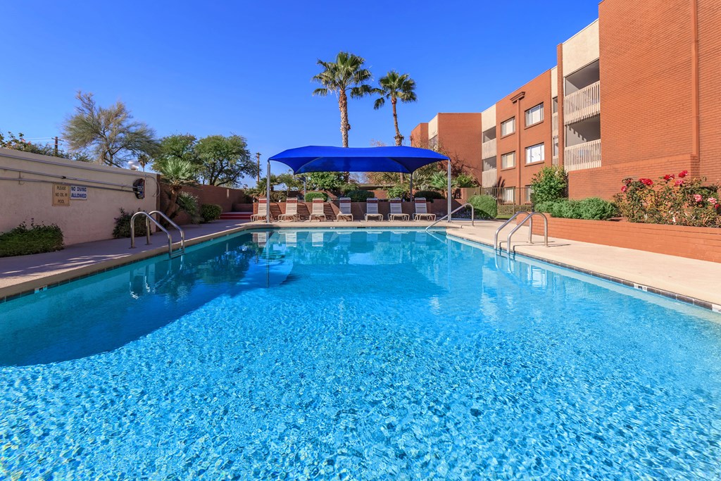 A swimming pool with a blue umbrella and a building in the background.