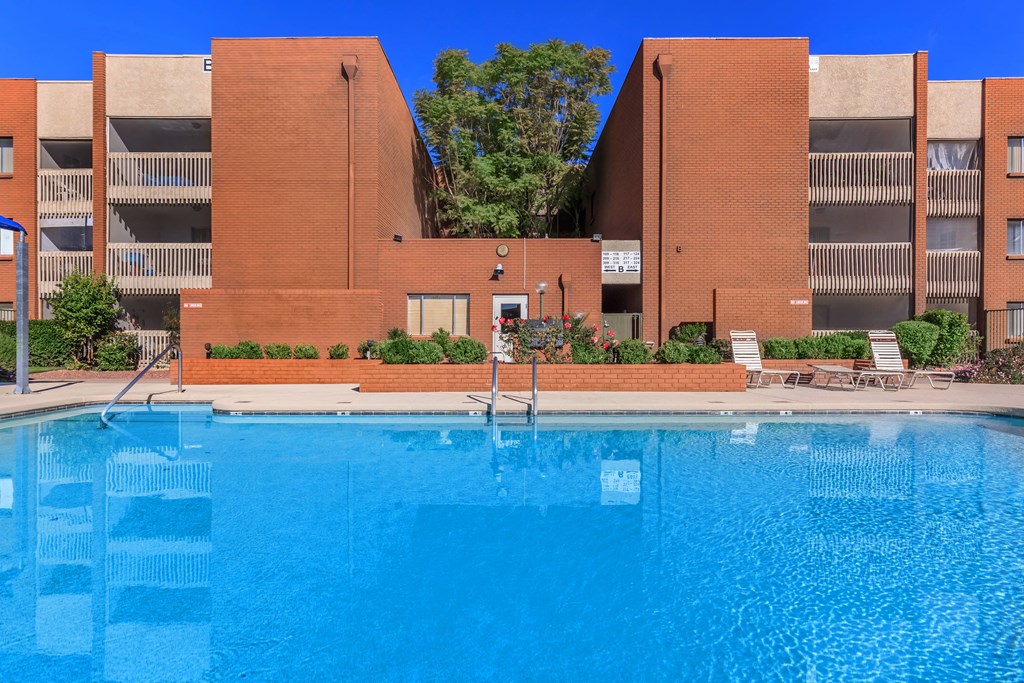 A swimming pool in front of a red brick building.