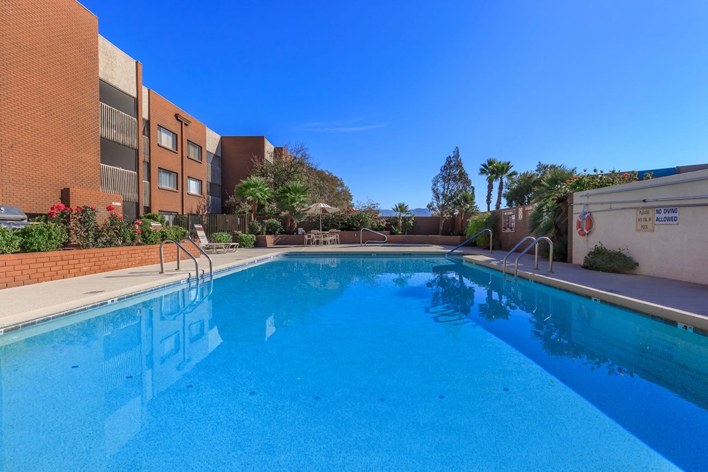 A swimming pool in front of a building with a red brick wall.
