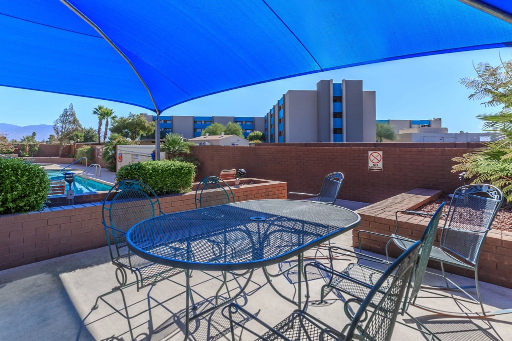 A patio with a table and chairs under a blue umbrella.