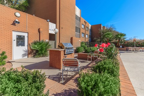 A brick building with a bench and a planter with red flowers.