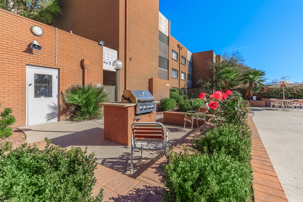 A brick building with a bench and a planter with red flowers.