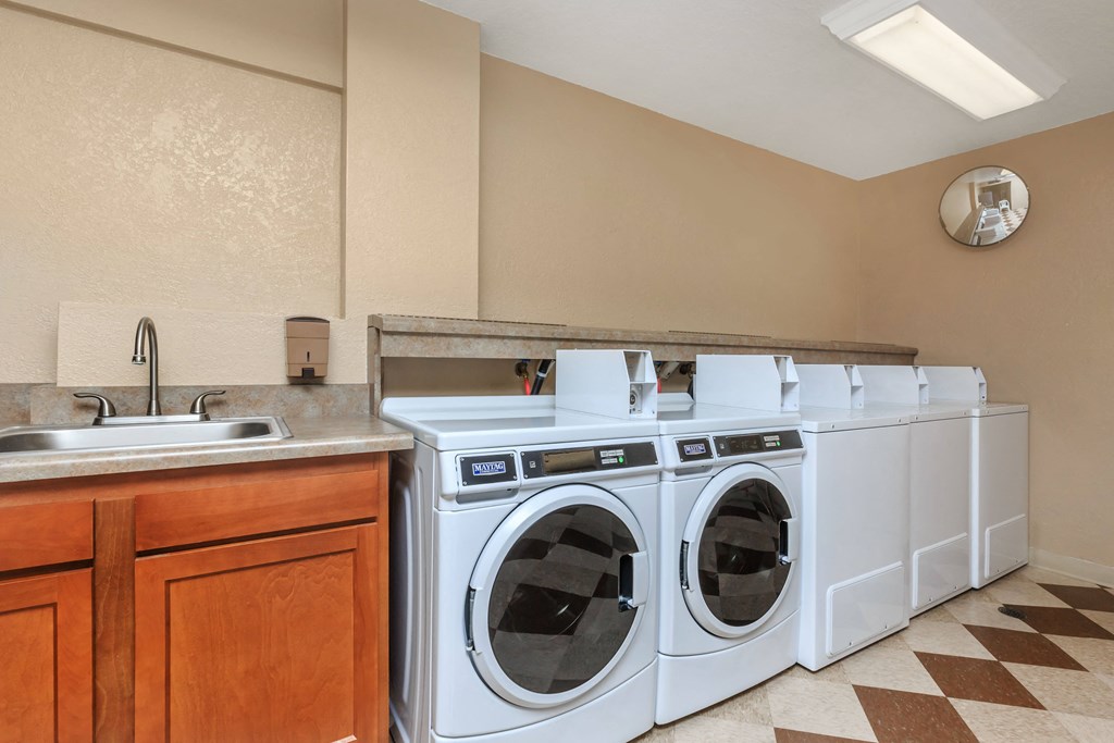 A row of white front loading washing machines in a laundry room.