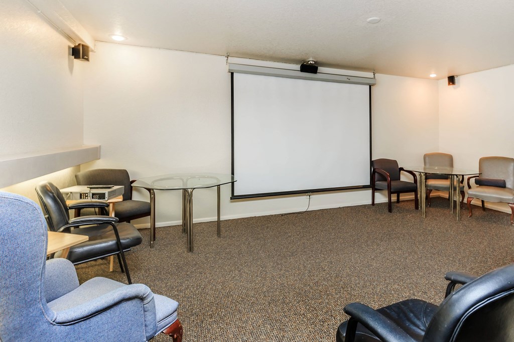 A conference room with a white screen and chairs.
