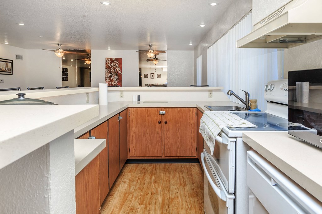 A kitchen with white countertops and wooden cabinets.