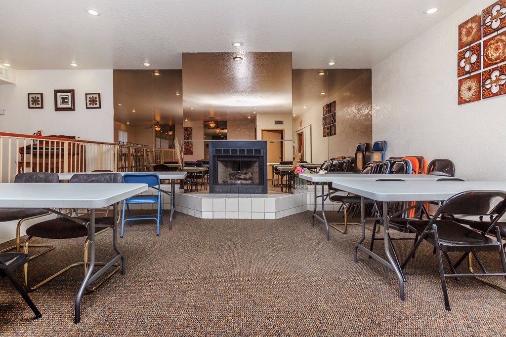 A room with a fireplace, chairs, and tables.