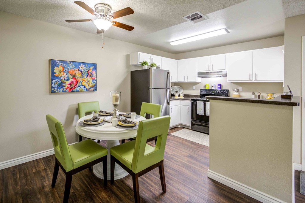 a dining room table and chairs with a kitchen in the background