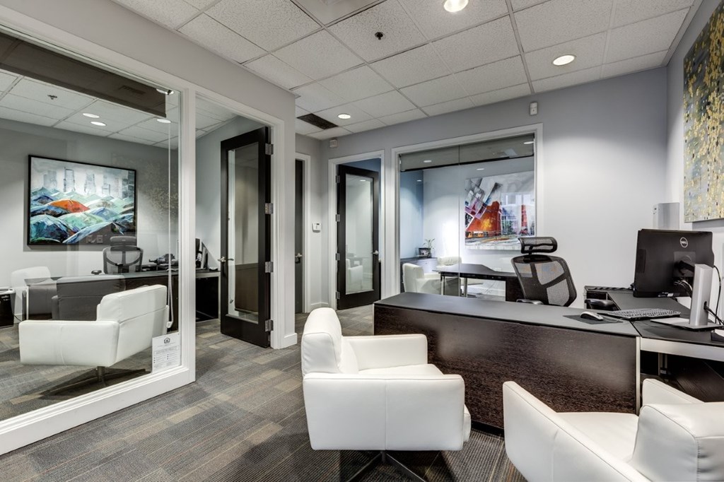 A modern office with white chairs and a glass wall.