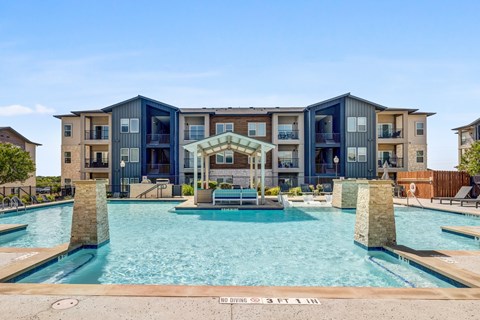 A large swimming pool in front of a modern apartment building.