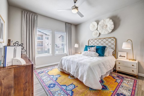 A bedroom with a white bed and a ceiling fan.