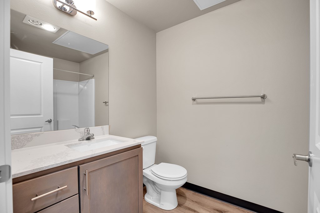 A white toilet sits in a bathroom with a sink and mirror.