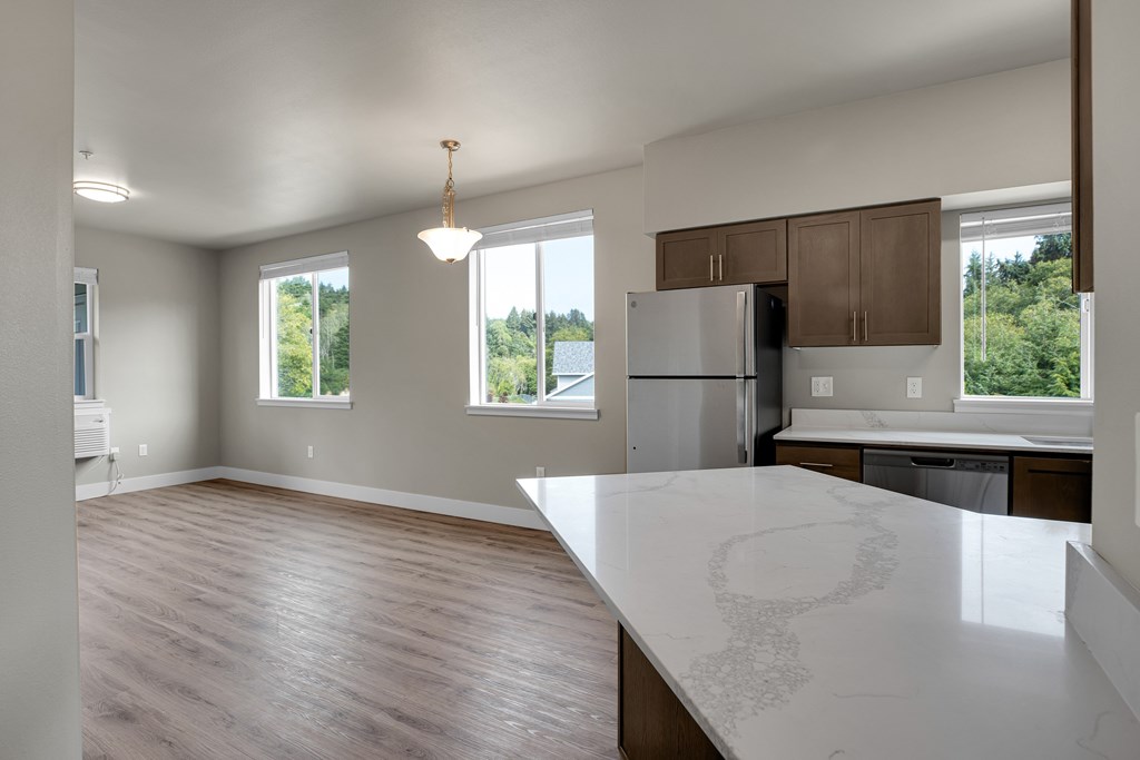 A kitchen with a white counter top and wooden floors.