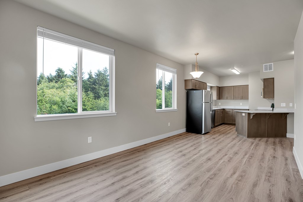 A spacious kitchen and living room with wood flooring and large windows.