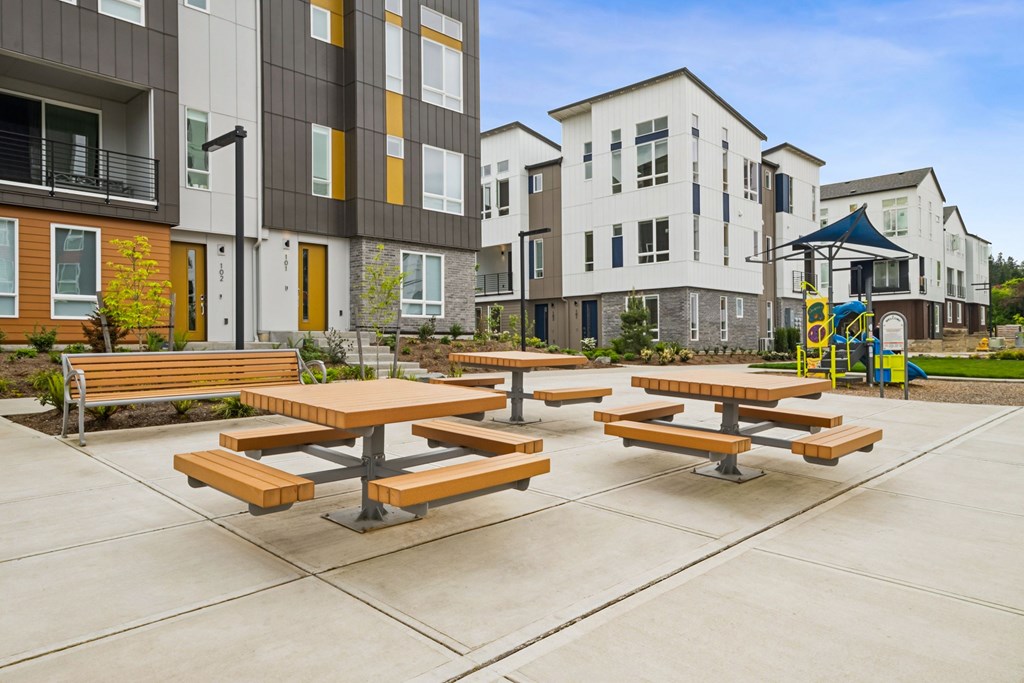 Picnic tables are set up in a courtyard between two buildings.