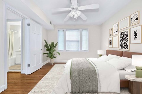 A bedroom with a bed, a ceiling fan, and a plant.