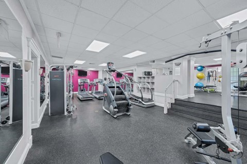 A gym with a variety of equipment including treadmills, weights, and exercise machines.