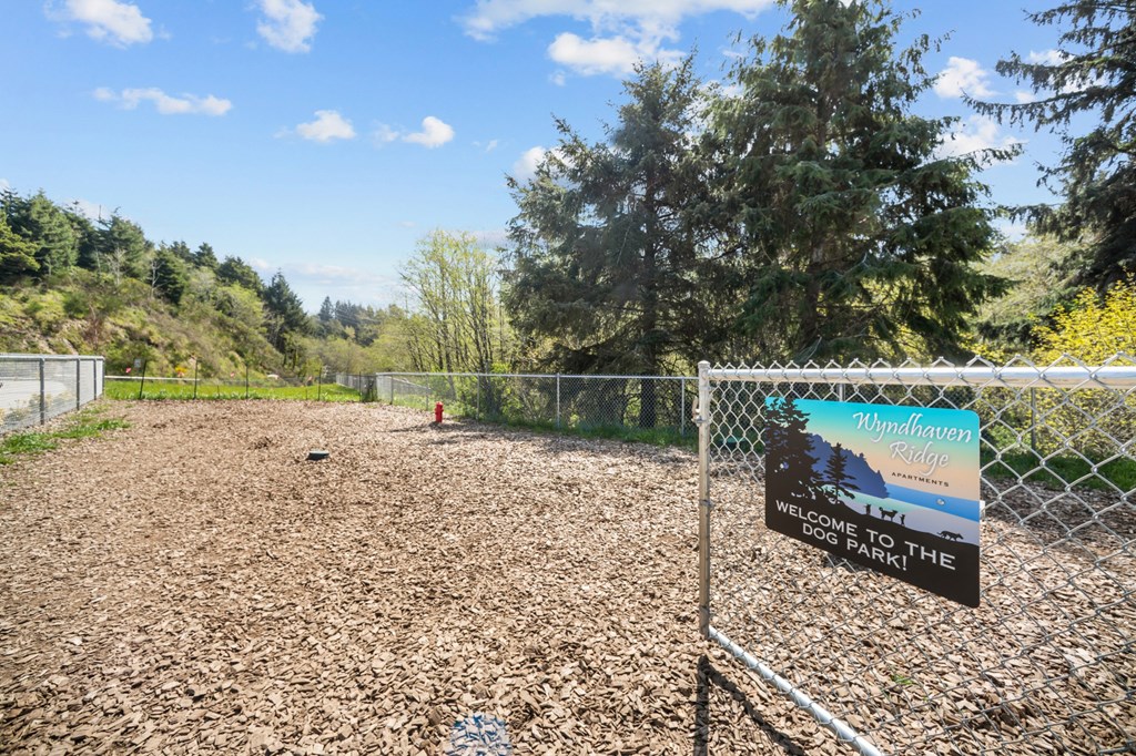 A sign welcoming people to a park stands in front of a fence.