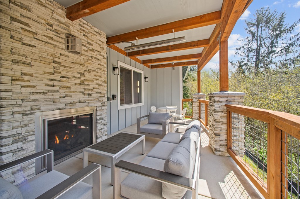A patio with a stone fireplace and grey couches.
