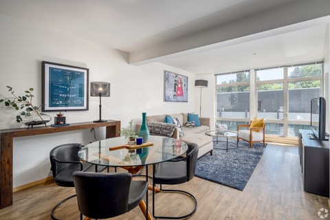 A modern living room with a glass table and black chairs.