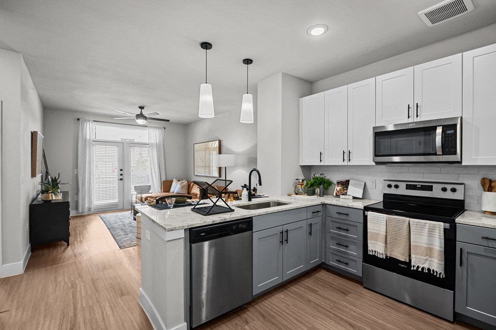 an open kitchen with stainless steel appliances and white cabinets at Lenox Grand, Texas, 78727