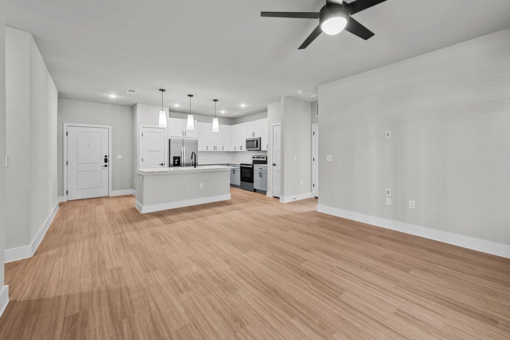 an empty living room and kitchen with a ceiling fan