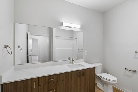 A bathroom with a white counter top and a white toilet.