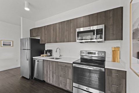 an apartment kitchen with stainless steel appliances and a refrigerator