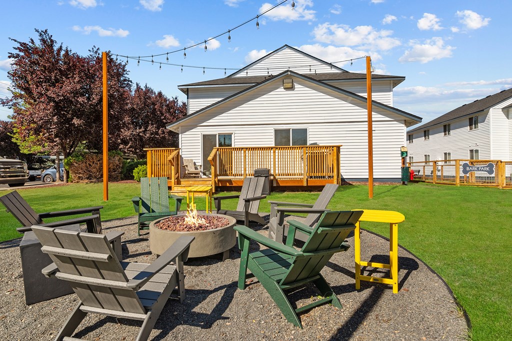 A fire pit surrounded by chairs in a backyard.