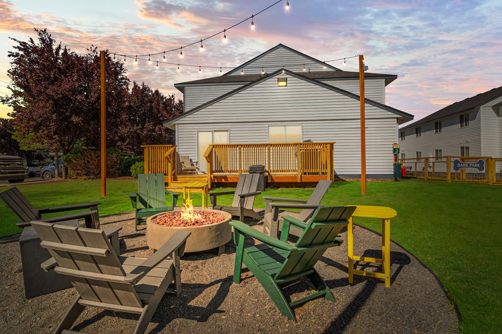 A fire pit surrounded by chairs in a backyard.