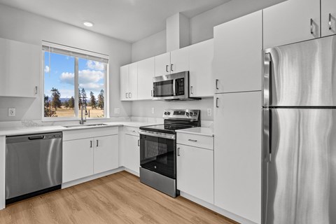 A modern kitchen with white cabinets and stainless steel appliances.