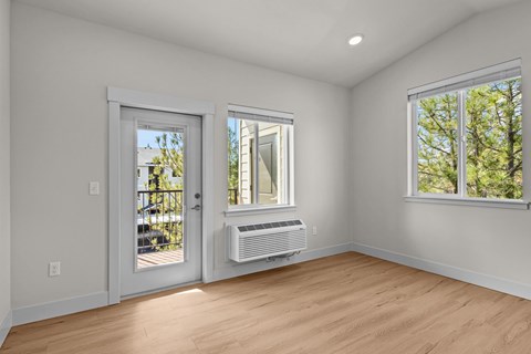 A room with a window and a door leading to a balcony.