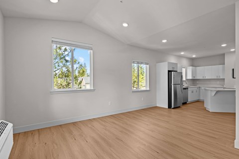 A spacious kitchen with wooden floors and white walls.