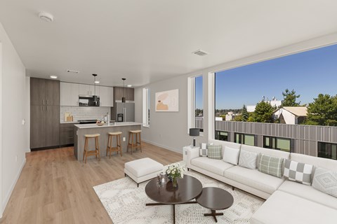 A modern living room with a kitchen area in the background.