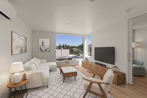 A living room with a white couch, a wooden coffee table, and a large window with a view of trees and buildings outside.