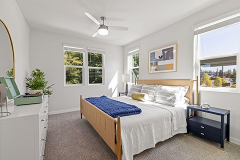 A bedroom with a bed, nightstand, and a plant.